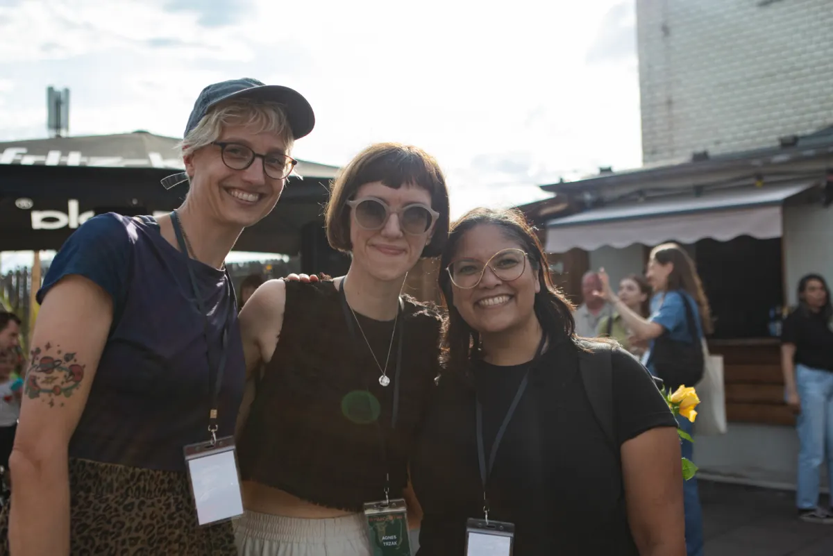 Three conference participants smiling together on the terrace