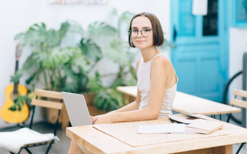 Woman in White Dress Wearing Eyeglasses Holding Laptop on Her Knees