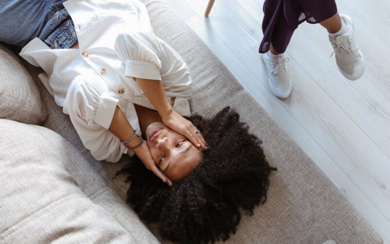 A Problematic Woman Lying on the Couch with Her Hands on Her Face