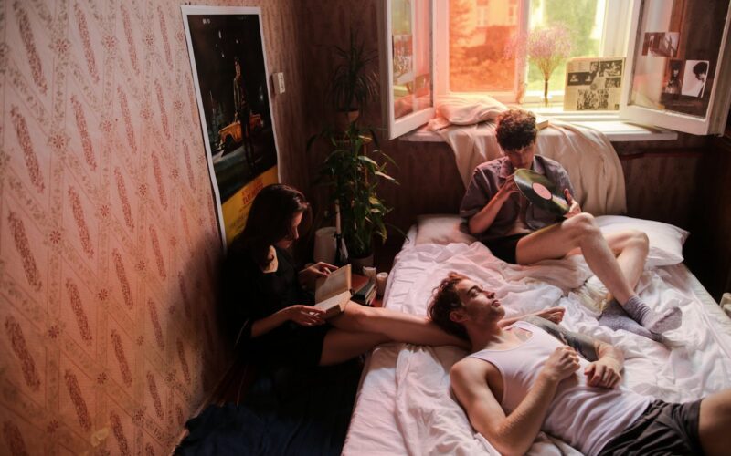 Man in Blue T-shirt Lying on Bed Beside Woman in Green T-shirt