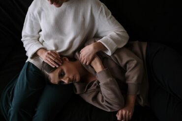 Woman in White Turtleneck Sweater Lying on Black Textile