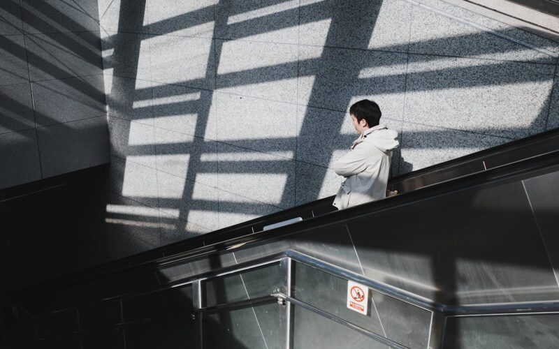 Man on Escalator with Geometric Shadows