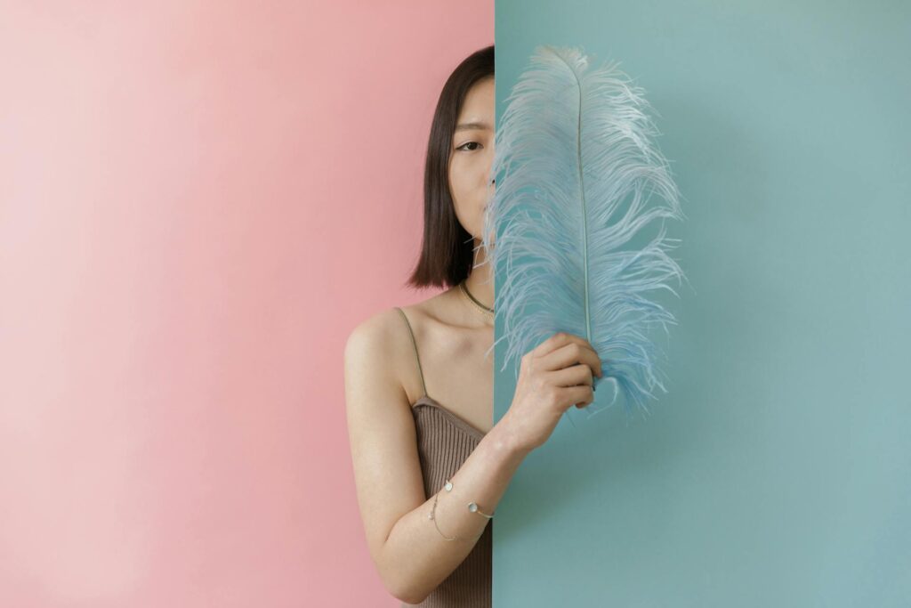 Woman in Brown Stripe Tube Top Holding Blue Feather