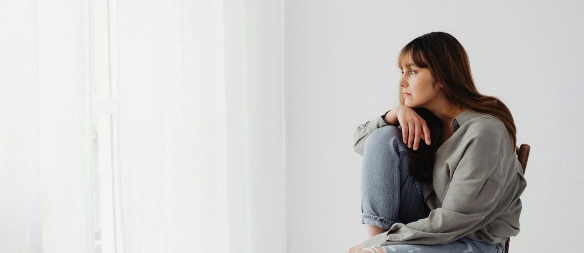 A Woman in Gray Long Sleeves Sitting on Chair Looking Pensive