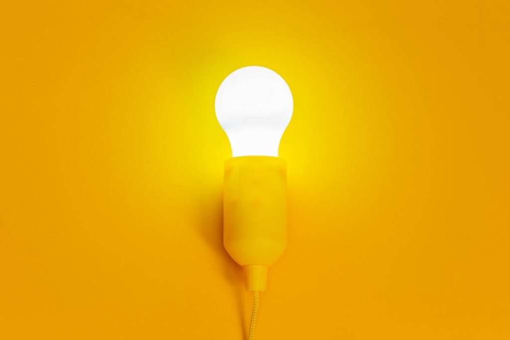 White Light Bulb Turned on in Yellow Background