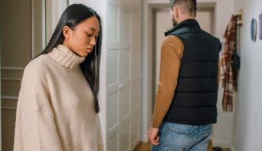 A Woman in Cream Sweater Behind a Person in Black Vest