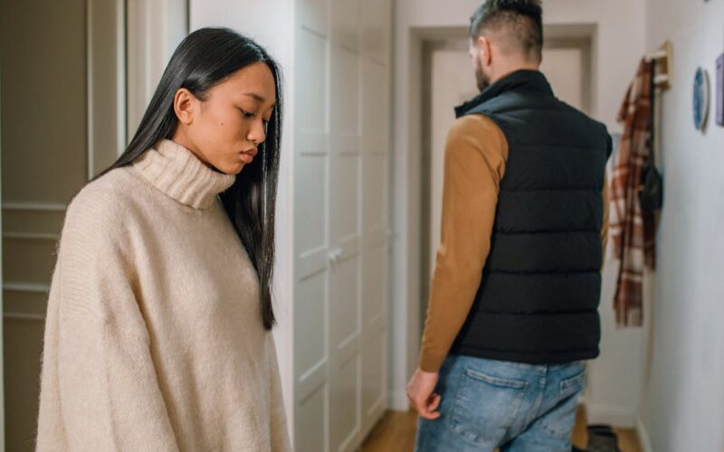 A Woman in Cream Sweater Behind a Person in Black Vest
