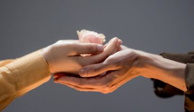 Close-up of Man and Woman Touching Hands and Woman Holding a Rose Flower Head