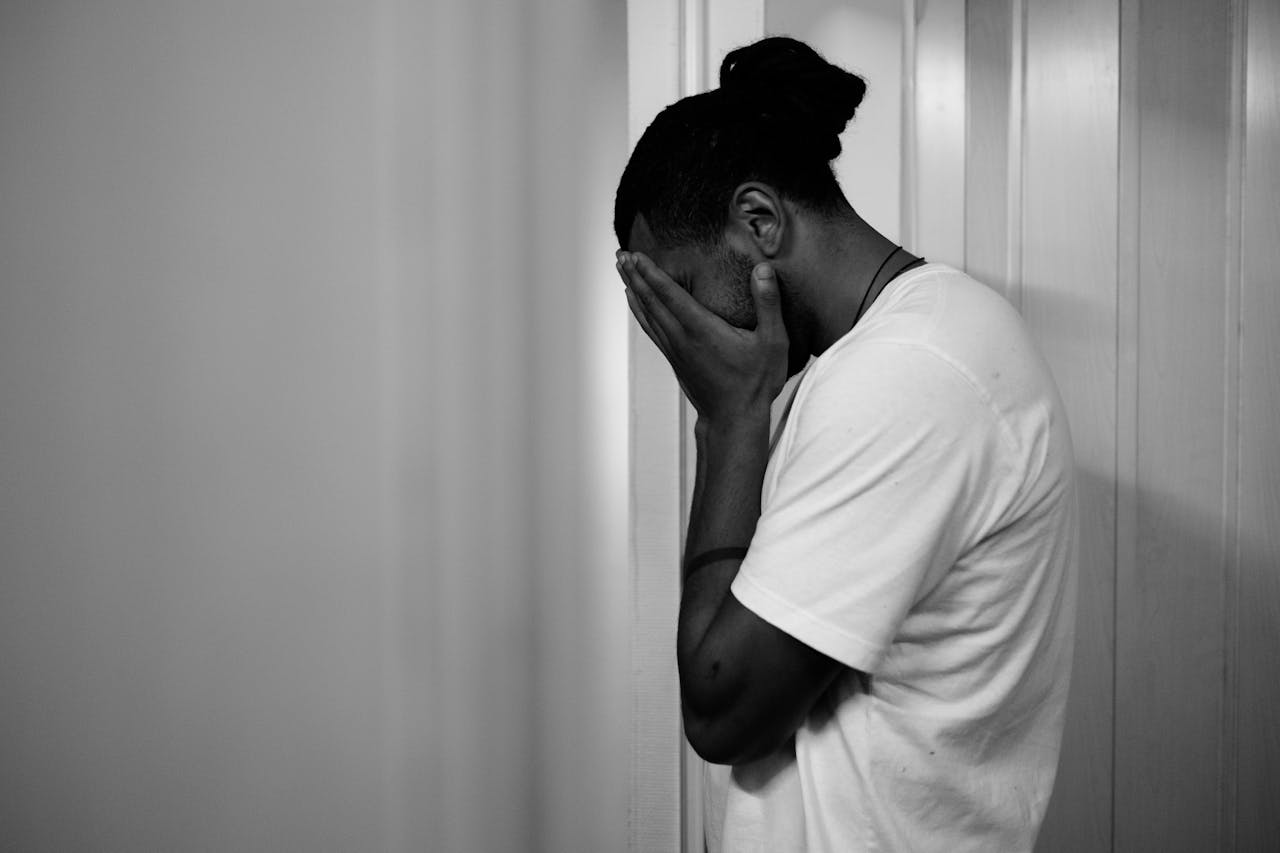 A black and white image of a man with his head in his hands.