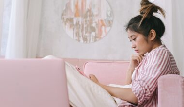 Woman in Pink and White Stripe Shirt Using Her Phone on Sofa