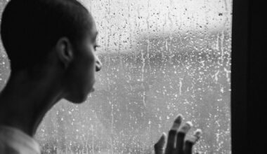 Thoughtful woman standing near window at rainy day