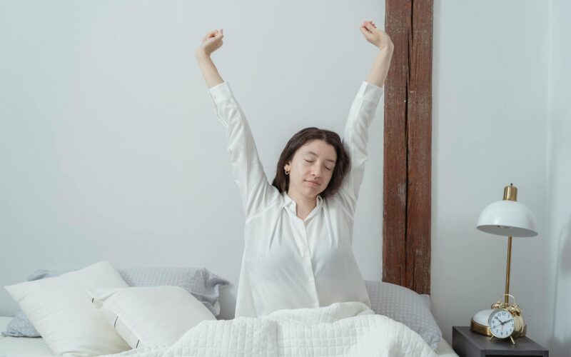 Sleepy woman waking up on bed in morning