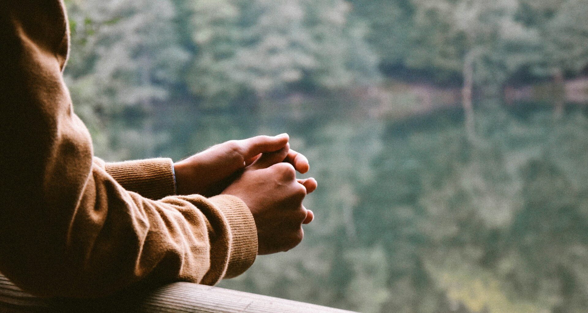 A woman contemplates while looking at a lake. Many expats experience mental health issues including depression.