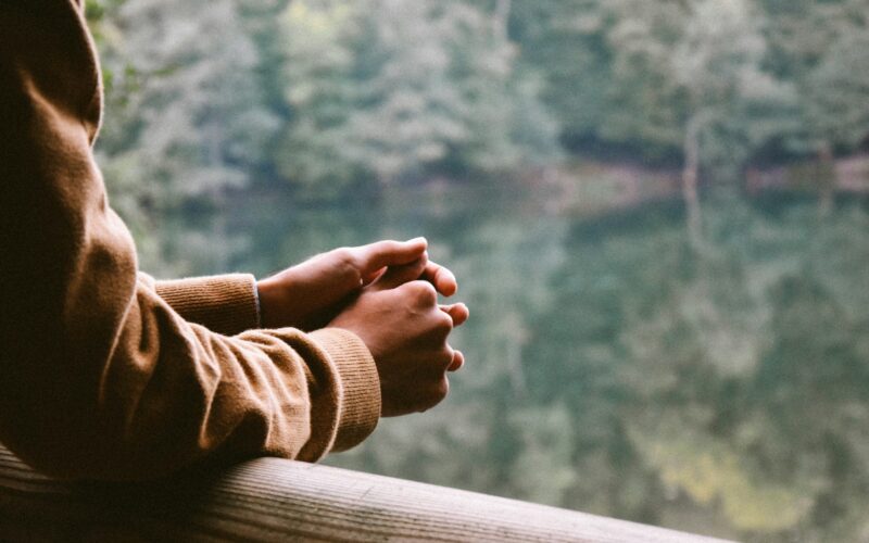 A woman contemplates while looking at a lake. Many expats experience mental health issues including depression.