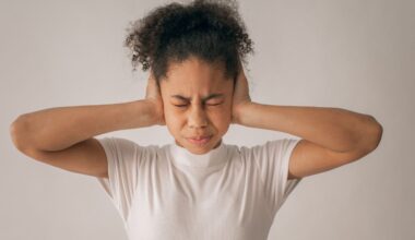 Teen girl with eyes closed and hands on ears in studio, feeling stressed.
