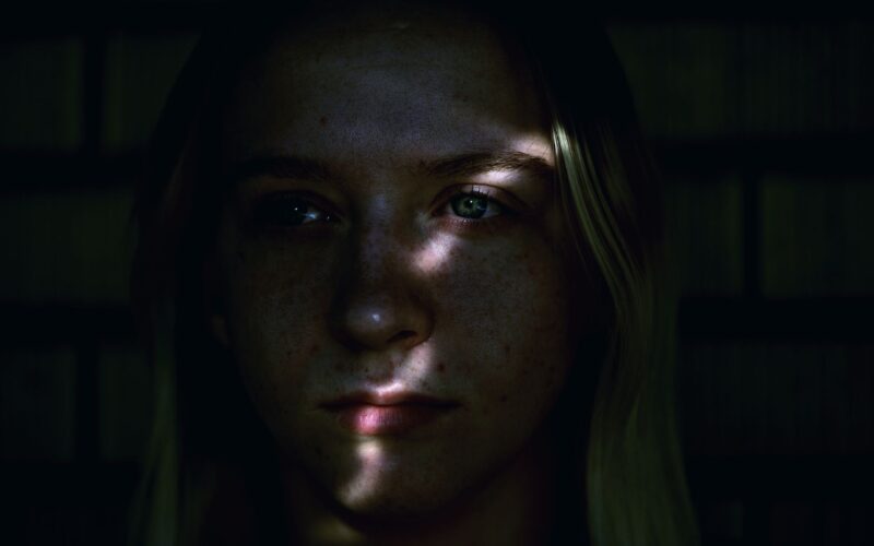 A young adult in shadows captures a moment of introspection and contemplation
